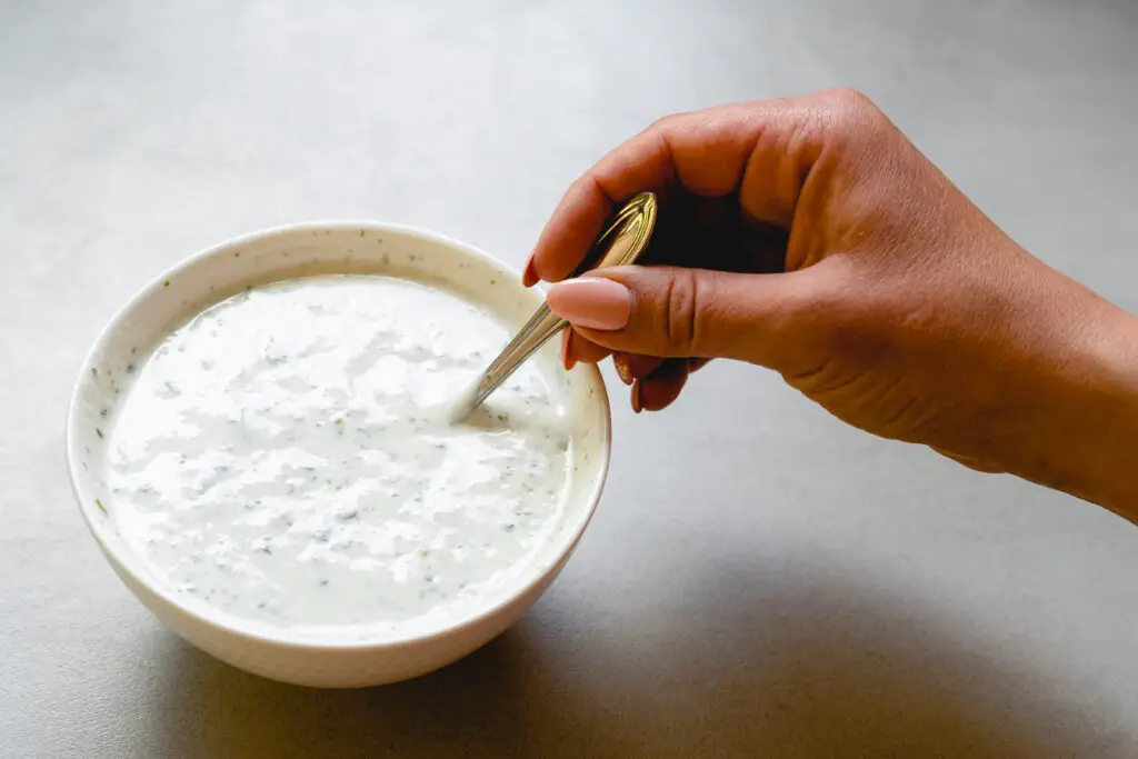 a person holding a spoon in a bowl of sauce