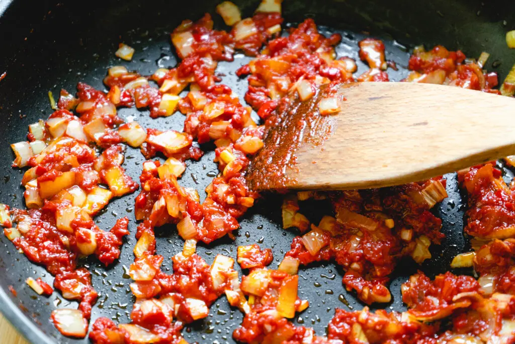 a wooden spoon stirring food in a pan